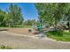 Playground with swings, climbing structure, and picnic tables in a park setting with mature shade trees at 7603 Yule Ct, Arvada, CO 80007