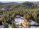 Aerial view of house and detached garage nestled in a dense forest at 636 Chute Rd, Golden, CO 80403