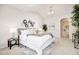 Cozy main bedroom with a comfortable bed, decorative wall art, and an arched entrance to the en-suite bathroom at 19377 E Radcliff Pl, Aurora, CO 80015