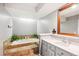 Bathroom with a large soaking tub, tile surround, gray walls, and a single sink vanity at 4675 S Yosemite St # 205, Denver, CO 80237