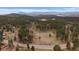 Expansive aerial view of a log cabin estate nestled within a lush green forest and rolling hills at 27888 Richmond Hill Rd, Conifer, CO 80433
