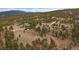 An aerial view of vast, wooded land with scattered homes and winding roads, showcasing a peaceful, rural community at 27888 Richmond Hill Rd, Conifer, CO 80433