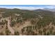 Scenic aerial perspective of a sprawling wooded landscape with winding roads, scattered homes, and distant mountain views at 27888 Richmond Hill Rd, Conifer, CO 80433
