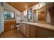Bathroom featuring a double vanity, wood cabinets, wood ceiling, and views of the forest through the windows at 27888 Richmond Hill Rd, Conifer, CO 80433