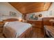 Comfortable bedroom featuring light wood paneling, an adjacent desk, and natural light at 27888 Richmond Hill Rd, Conifer, CO 80433