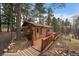 Charming log cabin with a wooden deck and walkway surrounded by trees on a sloped lot at 27888 Richmond Hill Rd, Conifer, CO 80433