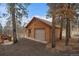 Log-sided garage featuring a neutral-tone door, adjacent to the home's deck, and surrounded by aspen and pine trees at 27888 Richmond Hill Rd, Conifer, CO 80433