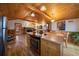 Open layout connecting the kitchen and living room, featuring a wood burning stove, and wood floors at 27888 Richmond Hill Rd, Conifer, CO 80433