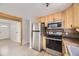 A kitchen with stainless steel appliances, light wood cabinets, and light grey walls with an opening to a hallway at 31168 Witteman Rd, Conifer, CO 80433