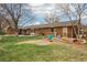 Expansive backyard with mature trees, a patio, a grill, and play equipment at 1324 State Highway 66, Longmont, CO 80504