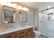 Bright bathroom featuring double vanity sinks, modern lighting and a glass shower with white tile at 6918 E Easter Pl, Centennial, CO 80112