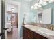 Bright bathroom featuring double sinks with granite counters, light blue walls, and a view into the bedroom at 7420 S Wolff St, Littleton, CO 80128