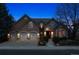 Charming home featuring a three-car garage, stone accents, and a manicured front yard, lit at dusk at 7420 S Wolff St, Littleton, CO 80128