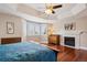 Bright main bedroom boasts a fireplace, hardwood floors, a ceiling fan, and a large bay window with plantation shutters at 7420 S Wolff St, Littleton, CO 80128