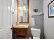 Charming powder room with a wood vanity, decorative mirror and fixtures, and a painted accent wall at 7420 S Wolff St, Littleton, CO 80128