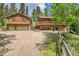 Inviting cabin-style home featuring wood siding, a spacious deck, and an attached two-car garage with large driveway at 11182 S Barney Gulch Rd, Conifer, CO 80433