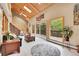 Bright living room with vaulted wood ceilings, large windows, a cozy fireplace and access to the deck at 11182 S Barney Gulch Rd, Conifer, CO 80433