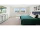 Bright bedroom featuring neutral walls, carpet, two windows, and a bed with an emerald green comforter at 17767 E 54Th Ave, Denver, CO 80249