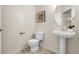 Half bath with a pedestal sink, a round mirror, and neutral colors at 3406 Purcell St, Brighton, CO 80601