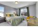Cozy bedroom with natural light, features grey walls, decorative bedding, and a comfy reading chair at 3406 Purcell St, Brighton, CO 80601