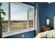 Bedroom with expansive window view featuring adjacent properties and a bright blue accent wall at 3406 Purcell St, Brighton, CO 80601