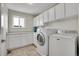 Bright laundry room equipped with modern washer, dryer, and ample cabinet space for storage at 3406 Purcell St, Brighton, CO 80601
