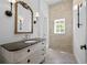 Elegant bathroom features a stone accent wall, decorative mirror, stylish vanity, and neutral herringbone floors at 5 Churchill Dr, Cherry Hills Village, CO 80113
