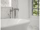 Close up of modern white bathtub with chrome fixtures, marble tile surround, and a natural light filled window at 5 Churchill Dr, Cherry Hills Village, CO 80113
