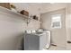 Bright laundry room with front load washer and dryer, storage shelf, neutral paint and tile flooring at 23757 Eagle Bend Ln, Parker, CO 80138