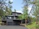 Exterior of the home featuring an attached two-car garage, balconies, and mature trees at 28833 Western Dr, Evergreen, CO 80439