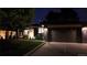 Charming single-story home featuring a sleek dark gray exterior, lush green lawn, and a modern garage door at night at 1830 S Fillmore St, Denver, CO 80210