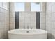 Close up of a freestanding tub in a stylish, tiled bathroom with windows at 16595 E 110Th Ave, Commerce City, CO 80022