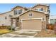 Tan two story home with a two-car garage and stone column accents on the front porch and garage at 17859 E 108Th Pl, Commerce City, CO 80022