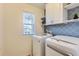 Laundry room featuring white appliances, patterned backsplash, and a window for natural light at 17859 E 108Th Pl, Commerce City, CO 80022