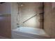 Bright bathroom featuring shower-tub combo, tiled walls and floors, and metal storage rack at 3288 W Tufts Ave, Englewood, CO 80110