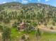 Aerial view of custom home nestled in wooded landscape with long driveway at 127 Granite Way, Evergreen, CO 80439