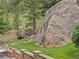 Landscaped backyard with a large boulder and mature trees at 127 Granite Way, Evergreen, CO 80439