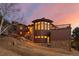 Stunning architectural details and a wall of windows highlight this home with a sunset backdrop at 127 Granite Way, Evergreen, CO 80439