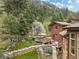 Exterior side view of the home with lush landscaping, boulder outcroppings, and mature trees at 127 Granite Way, Evergreen, CO 80439