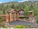 Beautiful exterior featuring a stone-and-siding design, manicured landscaping, and an expansive driveway with mountain backdrop at 127 Granite Way, Evergreen, CO 80439