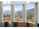 Breathtaking view of the surrounding mountain range from the living room with large windows and a deck at 127 Granite Way, Evergreen, CO 80439