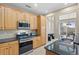 Well-lit kitchen with wooden cabinets, stainless steel appliances, granite countertops, and tile flooring at 10650 Ashfield St, Highlands Ranch, CO 80126