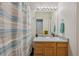 Well-lit bathroom with a wooden vanity, large mirror, and a neutral striped shower curtain at 19707 E Caspian Cir, Aurora, CO 80013