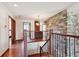 Bright hallway with wood floors, stone accent wall, and attractive wooden banisters at 984 Shadow Mountain Dr, Highlands Ranch, CO 80126
