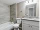 A clean bathroom featuring a shower over tub, granite countertop, and grey wood-look tile at 1777 S Pitkin St # A, Aurora, CO 80017