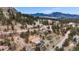 Sweeping aerial view of a blue home with an attached two car garage surrounded by trees and mountains at 248 Copperdale Ln, Golden, CO 80403