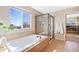 Bright bathroom features a soaking tub under a window and a glass-enclosed shower at 7765 Yankee Ct, Arvada, CO 80007