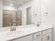 Bathroom featuring double sinks, quartz countertop, large mirror, and a glass shower, offering modern elegance at 14422 Pansy Loop, Morrison, CO 80465