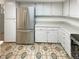A well-lit kitchen features white cabinets, stainless steel refrigerator and mosaic tile floor at 14822 E Adriatic Pl, Aurora, CO 80014