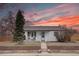 Charming home featuring a cozy front porch and beautiful landscaping under a vibrant sunset sky at 5191 S Logan St, Littleton, CO 80121